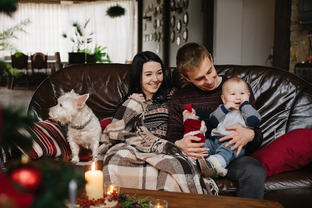 Foto grátis pais com um bebê no natal e um cão sentado no sofá