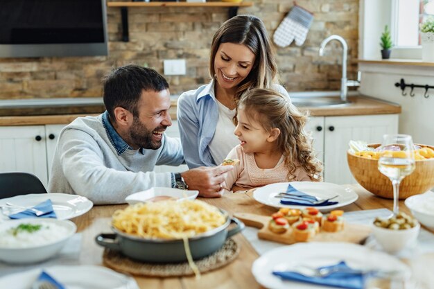 Pais felizes e sua filha de shopping se divertindo durante o almoço em família em casa