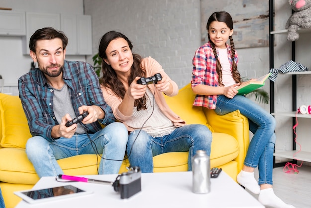 Foto grátis pais jogando videogame e filha olha para eles