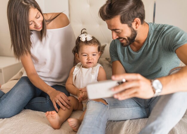 Pais jovens, mostrando, smartphone, para, menina bebê
