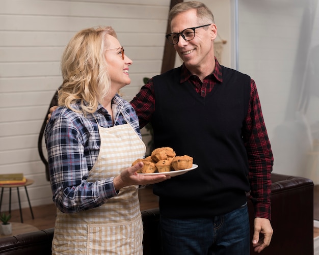 Foto grátis pais sorridentes segurando o prato com muffins