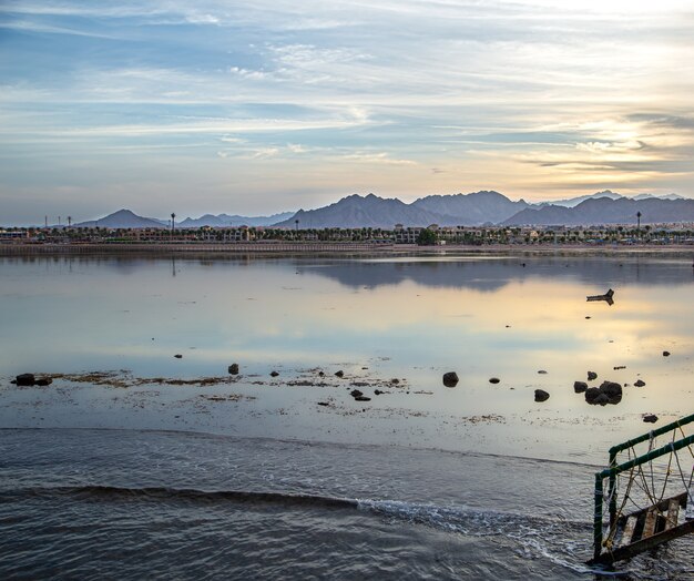 Paisagem de belo espaço ao pôr do sol à beira-mar. Com figuras solitárias à distância.