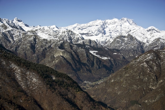 Paisagem de montanhas cobertas de árvores e neve sob a luz do sol e um céu azul