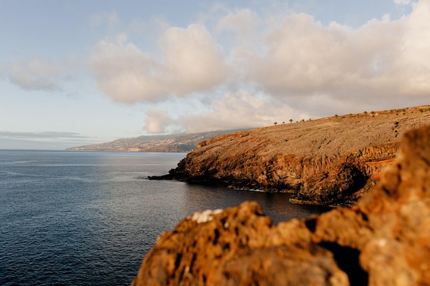 Foto grátis paisagem de um amplo oceano azul calmo com rochas laranja selvagens ao pôr do sol poder da natureza liberdade viagens