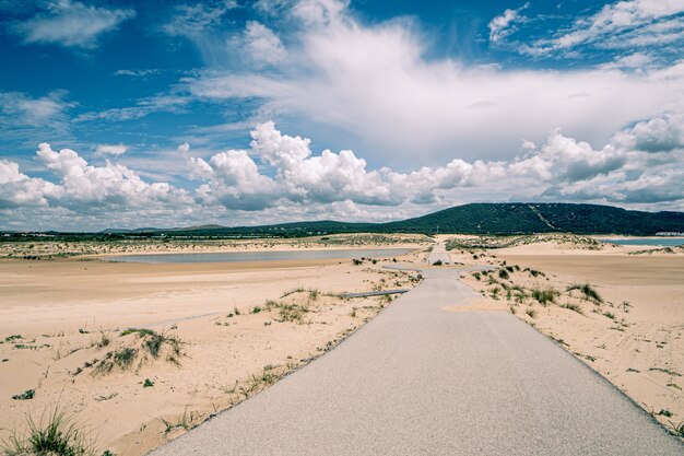 Paisagem de uma estrada vazia, algumas colinas no horizonte e nuvens fofas no céu