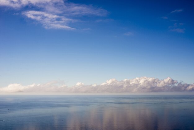 Paisagem do mar sob o sol com as nuvens refletindo na água em Portugal