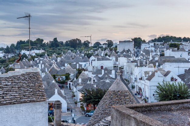 Paisagem urbana sedutora sobre os telhados tradicionais dos Trulli, casas originais e antigas desta região, Apúlia. Edifícios típicos caiados de branco construídos com paredes de pedra seca e telhados cônicos.