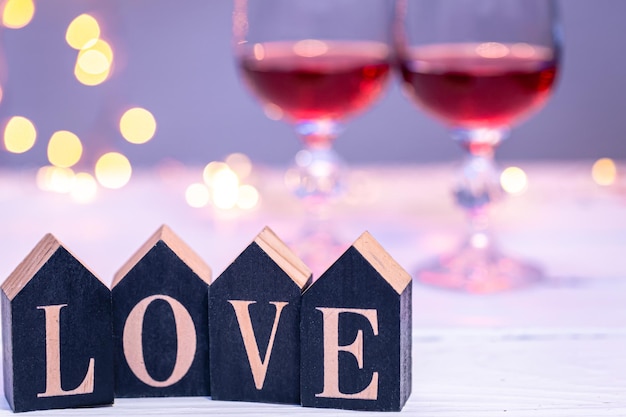 Palavra decorativa amor em um fundo desfocado com taças de vinho