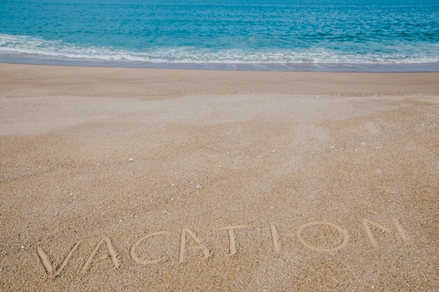 Palavra escrita sobre areia e oceano