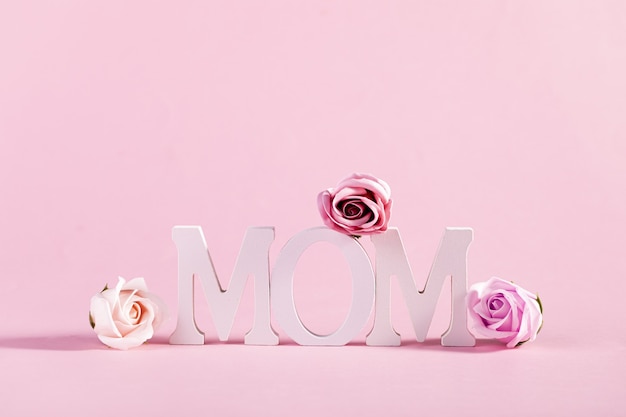Palavra "mamãe" decorada com flores em fundo rosa pastel