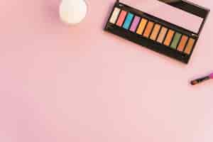 Foto grátis paleta de maquiagem com pincel sobre fundo colorido