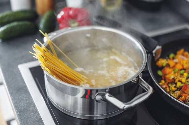 Panela a ferver com cozinhar macarrão espaguete na cozinha. Fechar-se