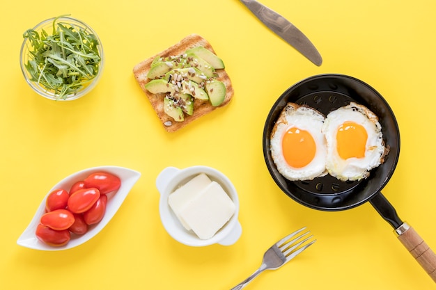 Panela com ovos fritos e torradas no café da manhã na mesa