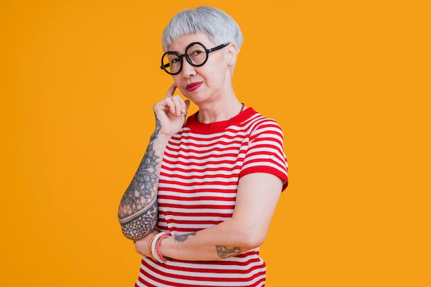 Foto grátis pano em forma de cabelo grisalho feminino asiático sênior com tatuagem braço em pé gesto com a expressão confiante positiva velha ásia mulher veste camiseta vermelha estilo de vida despreocupado felicidade idade de pensão