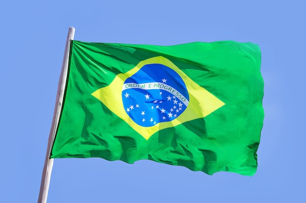 Pano têxtil da bandeira nacional do brasil acenando no topo, céu azul brasil, conceito de patriotismo Foto Premium