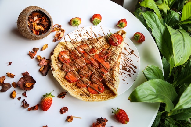 Panqueca coberta com fatias de morango e chocolate