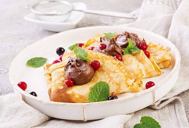 Panquecas com frutas e chocolate decorado com folhas de hortelã. Saboroso café da manhã.