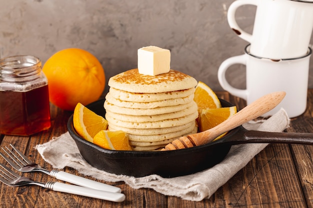 Foto grátis panquecas na panela com dipper e pote de mel