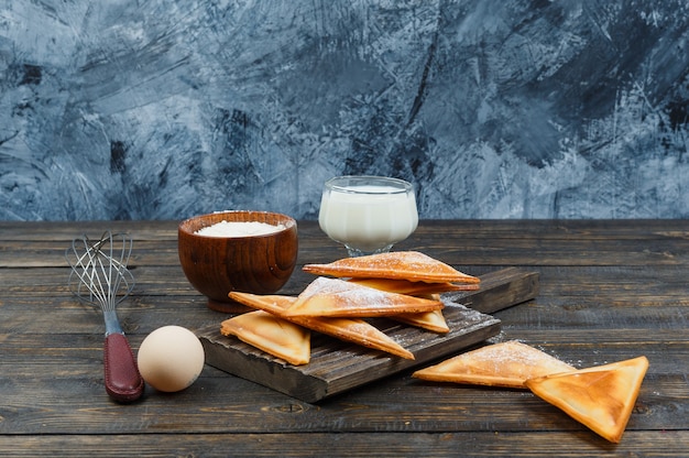 Panquecas na tábua de madeira com leite e ovo