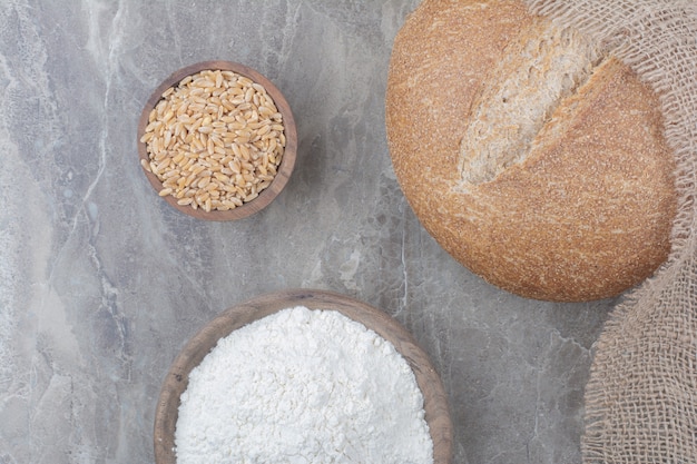 Pão branco com grãos de aveia e farinha na superfície de mármore