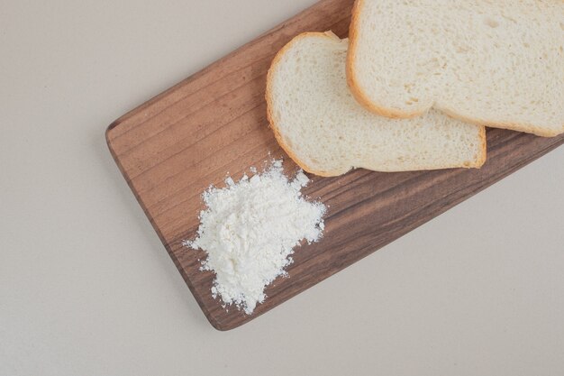 Pão branco fatiado com farinha na tábua de madeira