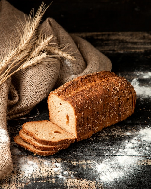 pão branco fatiado de pão com sementes de trigo e farinha na mesa