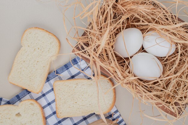 Pão branco fresco fatiado com ovos na toalha de mesa