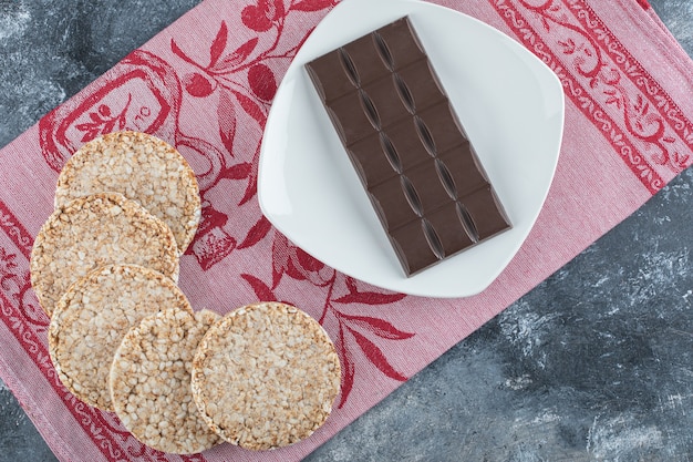 Pão de arroz crocante com barra de chocolate em uma toalha de mesa.