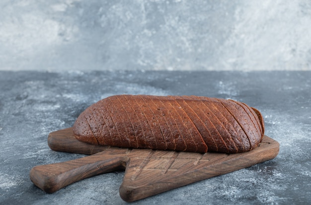 Foto grátis pão de centeio caseiro orgânico pumpernickel cortado em fatias na tábua de madeira. foto de alta qualidade