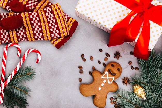 Pão de gengibre de Natal, grãos de café, ramo de abeto, luvas quentes e caixa presente no chão cinzento