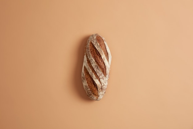 Pão de grão integral francês crocante caseiro fresco preparado com farinha orgânica, feito com fermento, isolado no fundo marrom do estúdio. Conceito de padaria e comida. Cozinhando em casa e preparação de alimentos.