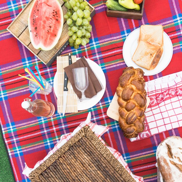 Pão de pão trançado acabado de cozer; frutas e pão na toalha de mesa quadriculada