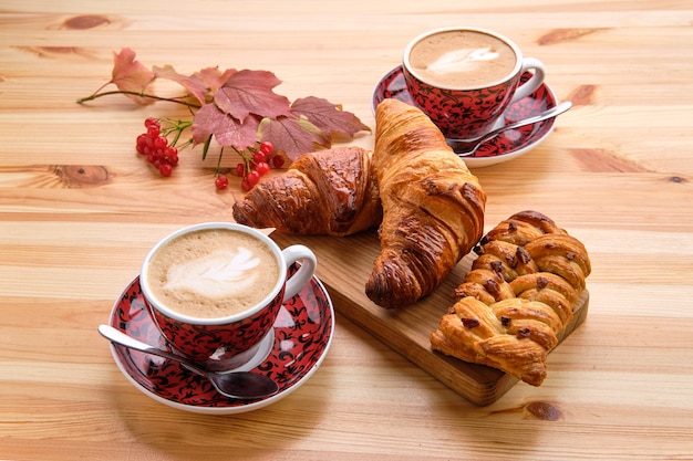 Pão de passas de massa folhada e croissant crocante na mesa de madeira com café Foto Premium