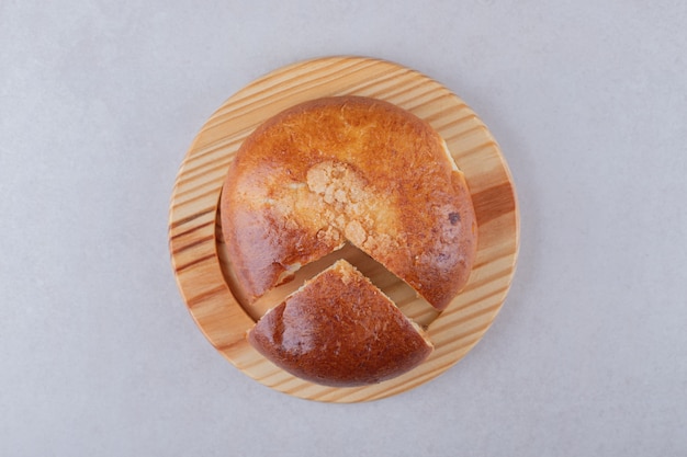 Pão doce fatiado na placa de madeira na mesa de mármore.