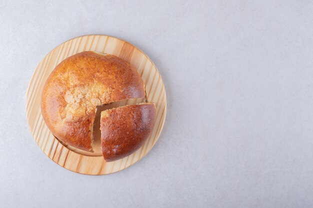 Pão doce fatiado na placa de madeira, no mármore.