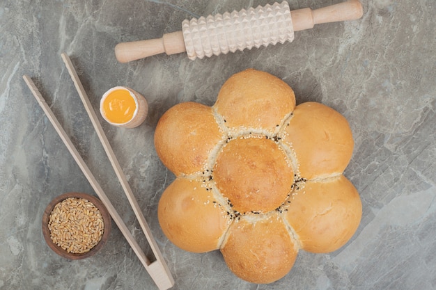 Pão em forma de flor com cevada e ferramentas na superfície de mármore. foto de alta qualidade