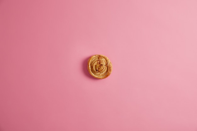 Pão espiral caseiro fresco para o seu saboroso café da manhã para satisfazer os gulosos. Apetitosa massa deliciosa com muitas calorias, fotorgada de cima sobre fundo rosa. Sobremesa aromática