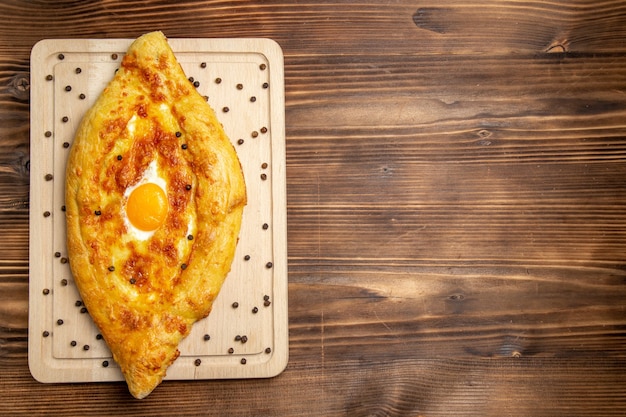 Pão fresco assado com ovo cozido em fundo marrom rústico massa café da manhã ovos pão comida