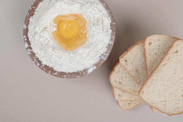 Pão fresco fatiado com tigela de madeira cheia de farinha