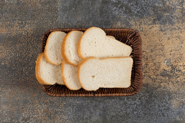 Pão fresco fatiado em cesta de madeira.