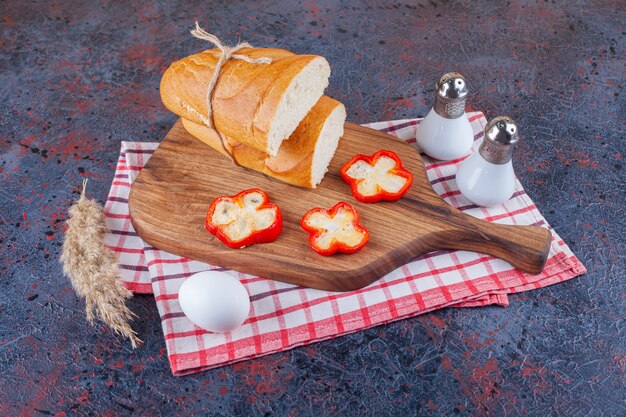 Pão fresco fatiado na placa de madeira e ovo cozido.