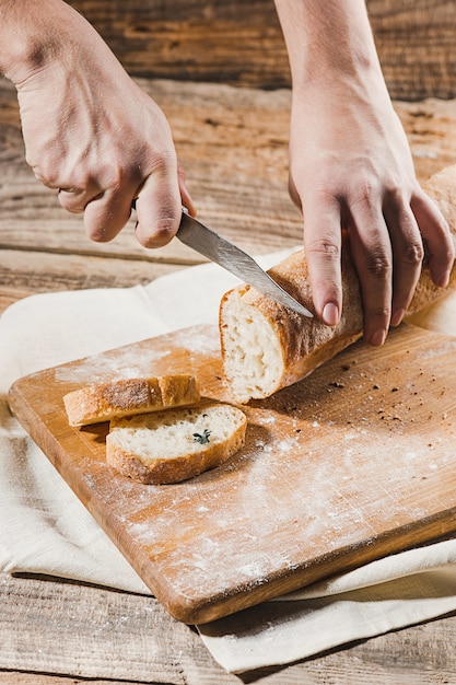 Pão integral, colocar na placa de madeira da cozinha com um chef segurando a faca de ouro para corte.