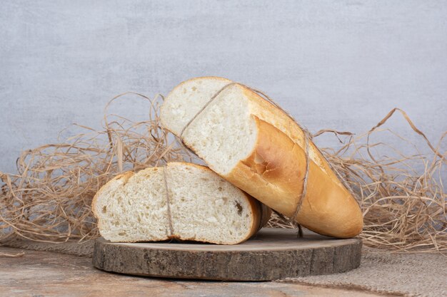 Pão meio cortado amarrado com corda em um pedaço de madeira