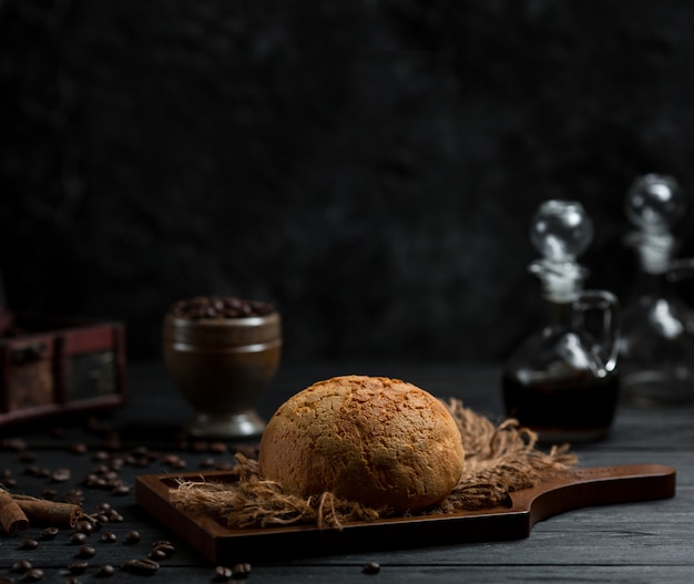 Pão redondo de pão homemae pn uma placa de madeira em um espaço muito escuro