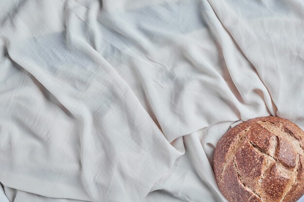 Pão redondo feito à mão em uma toalha de mesa branca.
