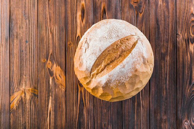 Pão redondo inteiro delicioso no fundo de madeira