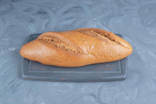 Foto grátis pão sentado em uma bandeja da marinha na mesa de mármore.