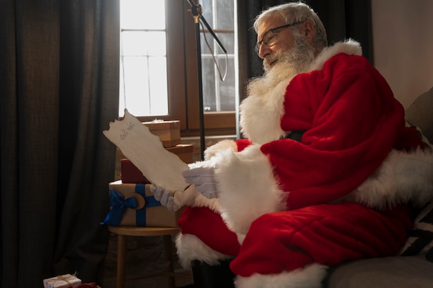 Foto grátis papa noel no sofá lendo uma carta