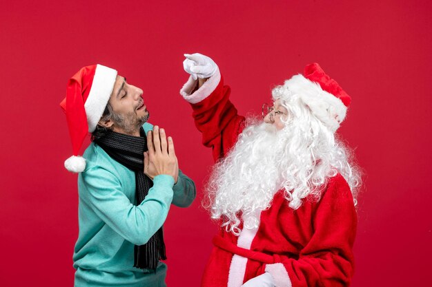 Papai Noel com um homem posando na mesa vermelha na frente do papai noel. Emoção de Natal