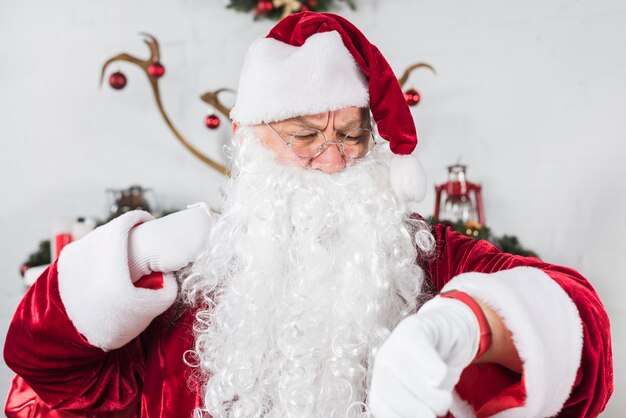 Papai Noel em copos, verificando o tempo no relógio de pulso